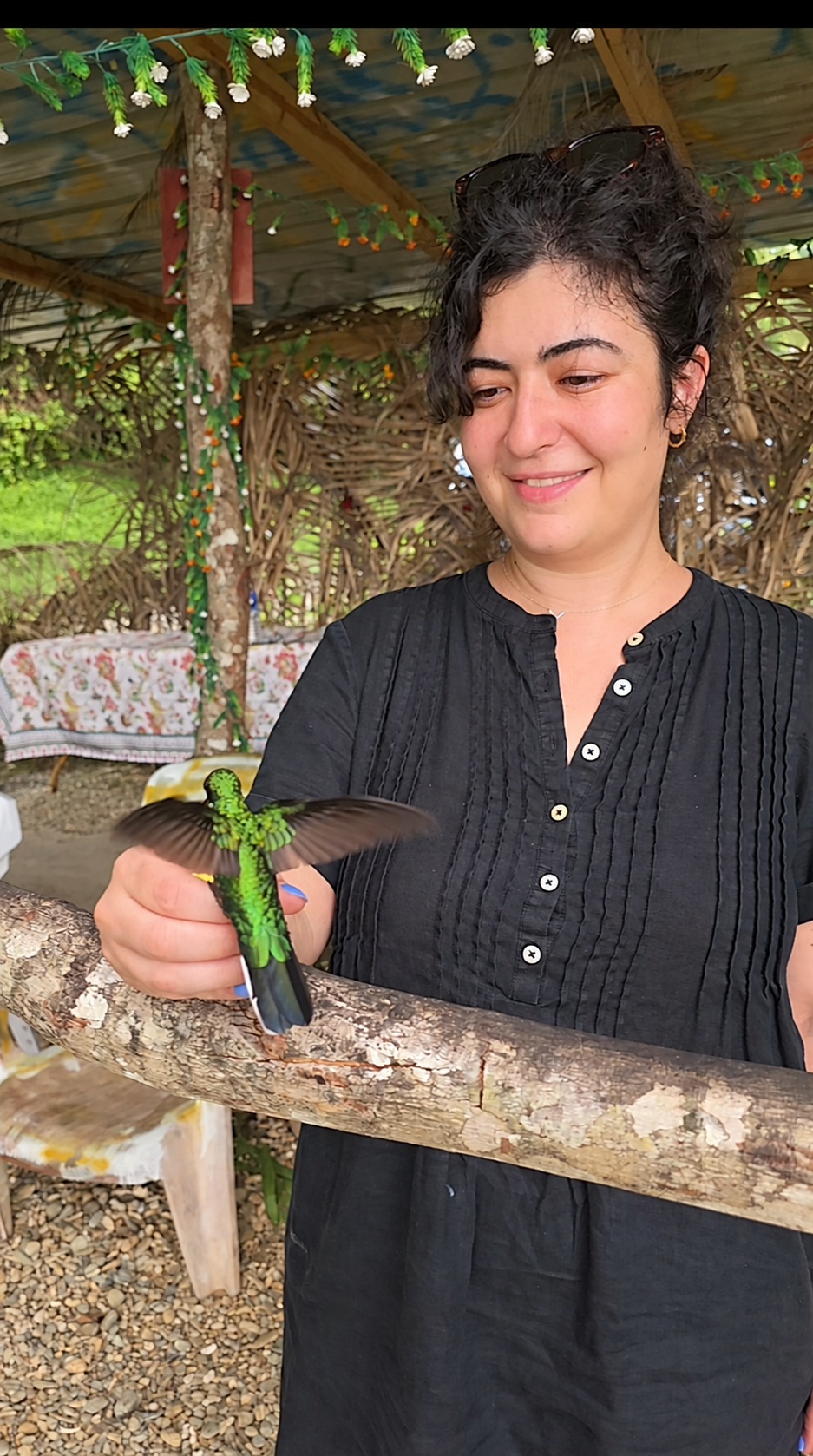 A woman feeding a brilliant green hummingbird by hand in Tobago