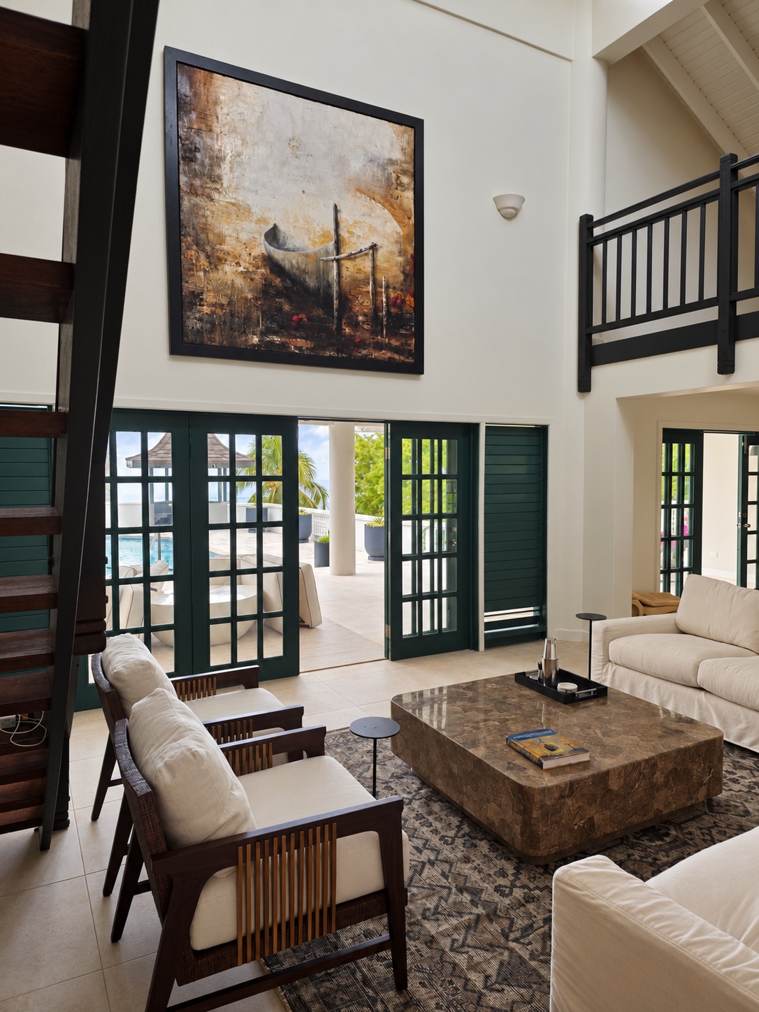 Sol Y Mar living room with cream seating, dark timber loft railings and doors opening to the pool terrace